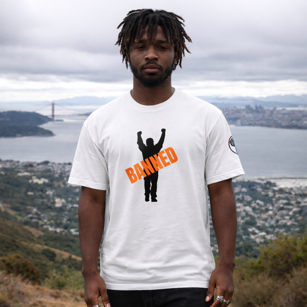 Person wearing a white t-shirt with 'BANNED' graphic in an outdoor setting